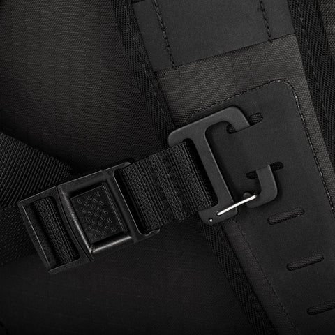 Close-up view of a black strap featuring a buckle and hook mechanism, attached to a piece of fabric, likely part of a modular accessory on the Cancha Padel & Pickleball Bundle bag or backpack.