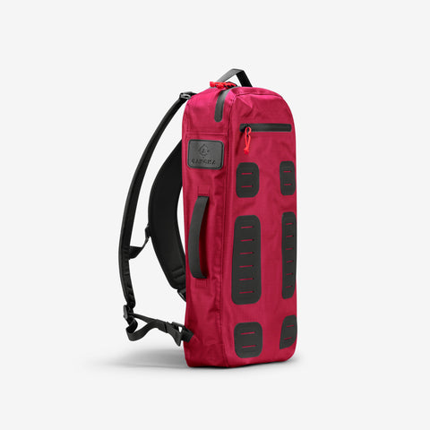 The Cancha Padel & Pickleball Bundle, a red backpack with black accents and multiple compartments, is designed to fit modular accessories and includes a black shoulder strap. The product is displayed against a plain white background.