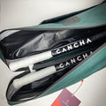 The Original Racquet Bag (15L) by Cancha is open, revealing two tennis racquets with white grips and 'Cancha' branding. A tag with the same branding is attached to a zipper.